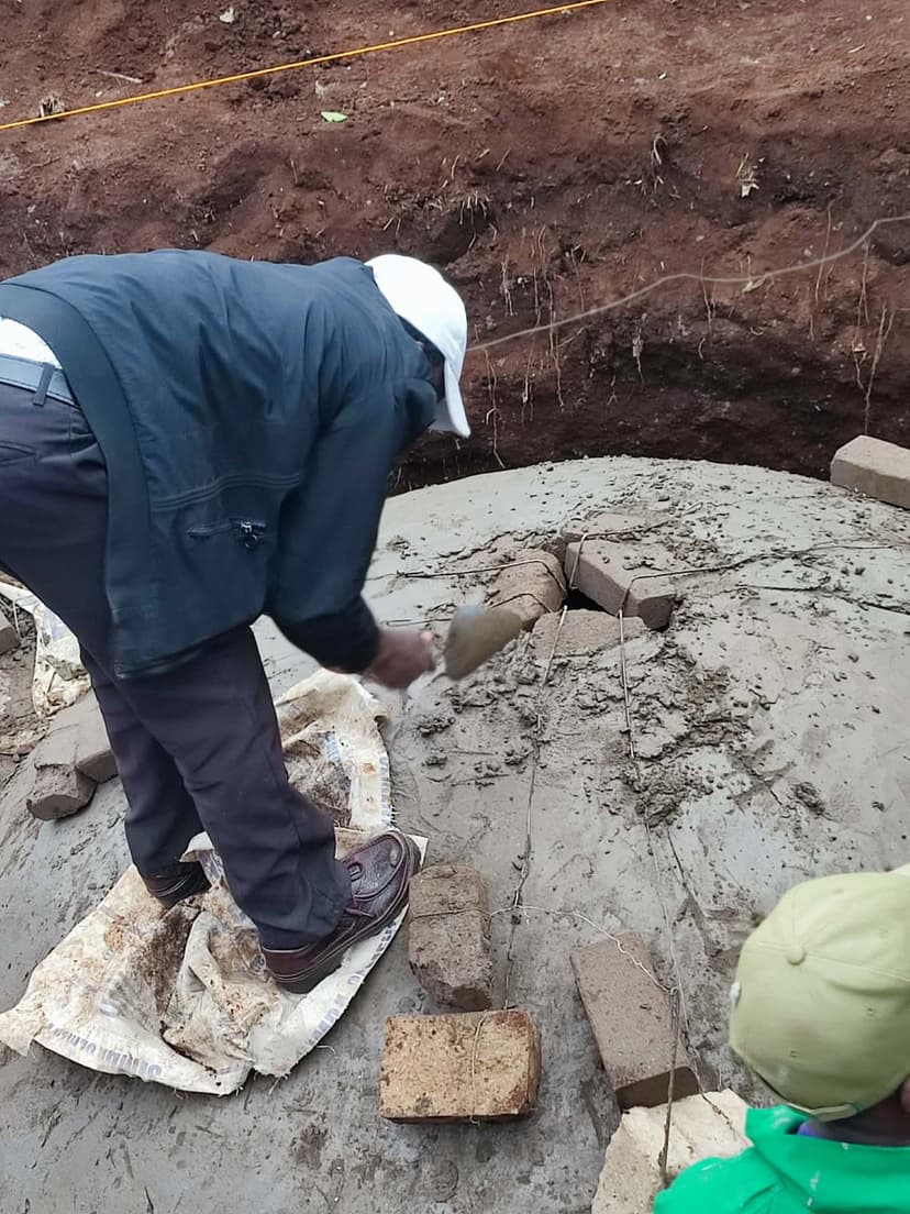 Technician plastering the outer dome of a biodigester