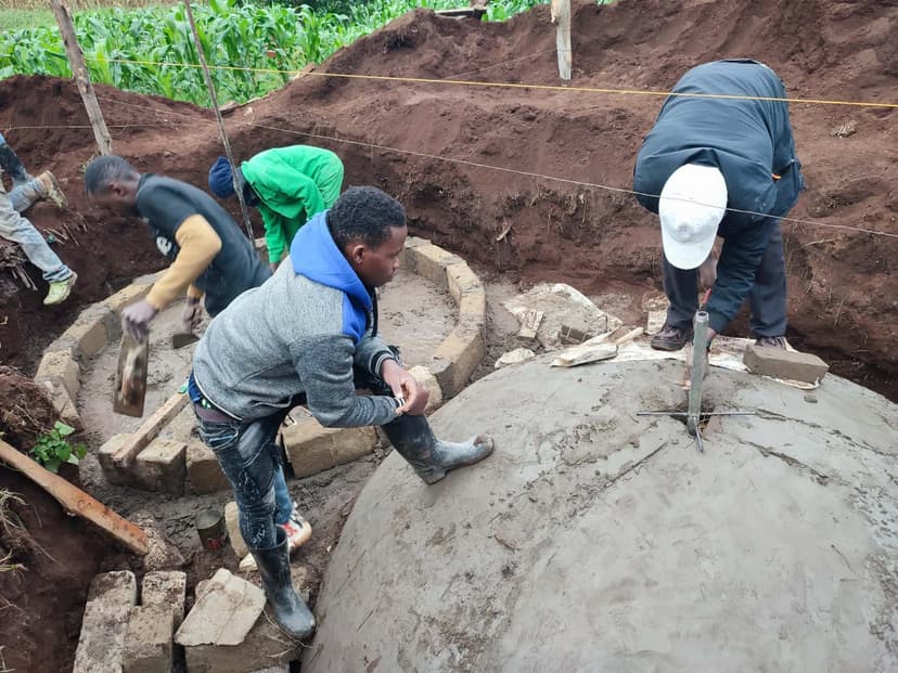 Team working around a digester dome with farmland in the background