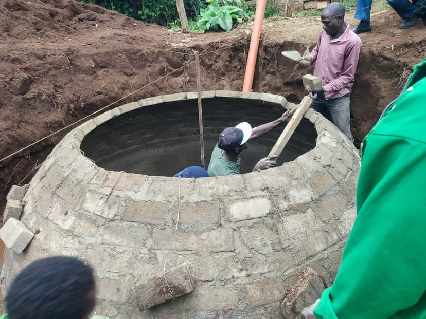 Technicians plastering the interior of a brick biodigester dome