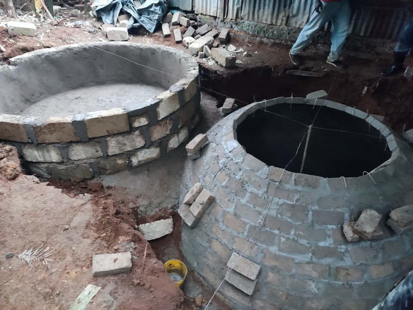 Two brick biodigester domes under construction side by side